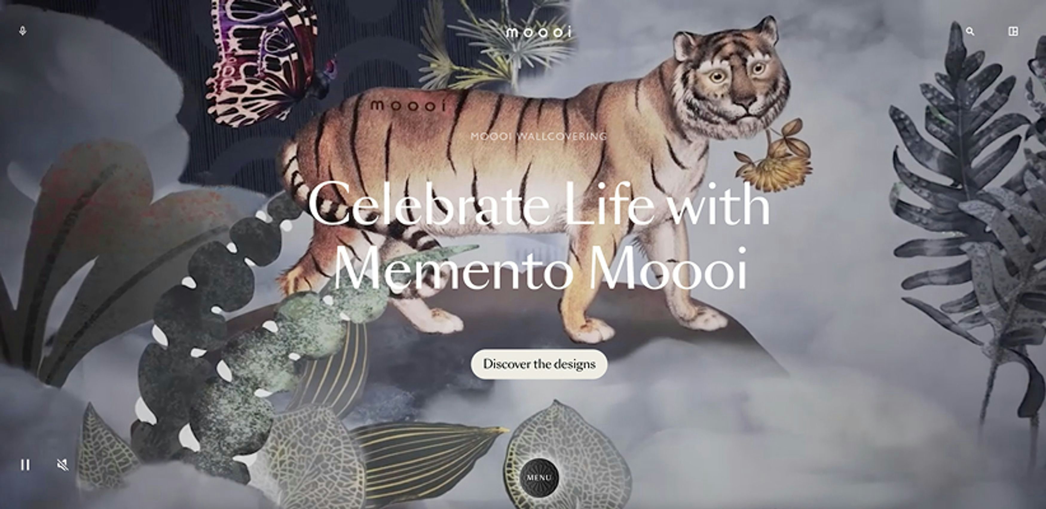 A promotional banner for Moooi wall covering featuring a digitally rendered tiger in the centre with wings, surrounded by exotic foliage and butterflies, with the text 'Celebrate Life with Memento Moooi' and a call-to-action button that reads 'Discover the designs'.