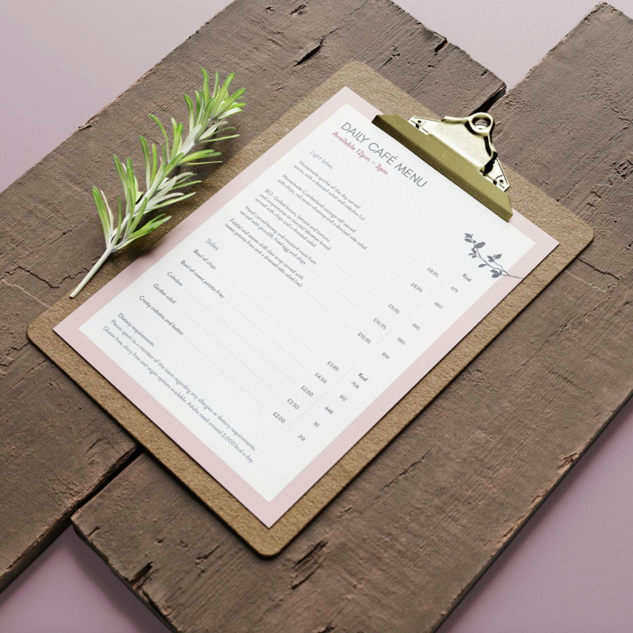 Daily cafe menu on a clipboard with a fresh sprig of rosemary, presented on a rustic wooden board with a pink background.